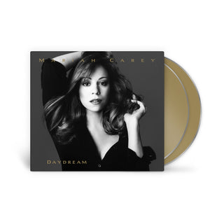 Mariah Carey's 'Daydream' vinyl record album, featuring a black-and-white cover photo of the artist and a gold-colored record partially visible behind the sleeve on a white background.