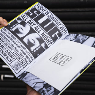 A person holds an open printed program or booklet showing black-and-white concert artwork and text for 'Slug' with a white insert page featuring the letters 'GHS'.