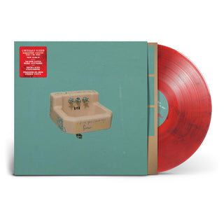 A vinyl record album with a turquoise cover featuring a sink illustration and a red sticker, shown with a translucent red vinyl record partially pulled from the sleeve on a white background.