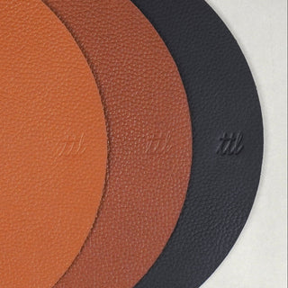 Three round textured leather-like pads or mats overlapping on a light gray background, shown in orange-brown, medium brown, and black.